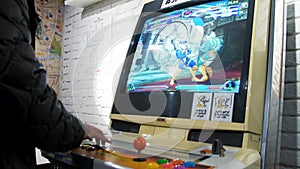 Detail of players hands interacting and playing with joysticks and buttons on an old arcade game in a gaming room