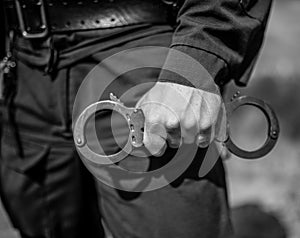 Detail of a police officer holding handcuffs.