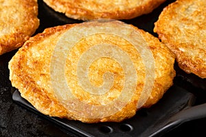 Detail of potato pancakes on cast iron frying pan with black spatula