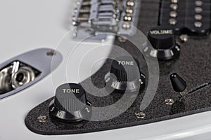 Detail of the potentiometers of a white electric guitar