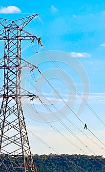 Detail of powerline assembly showing workers against blus sky