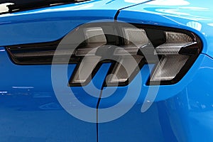 Detail of rear LED lights of modern electric american compact crossover car Ford Mustang Mach-E AWD, light blue color