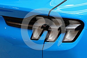 Detail of rear LED lights of modern electric american compact crossover car, light blue color, displayed on automobile expo.