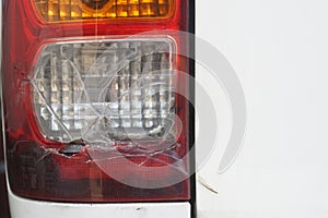 A detail of the rear light of a white car with broken glass.