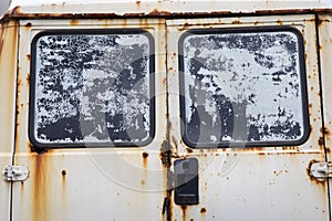 Detail of the rear window of an abandoned old white van with a lot of rust