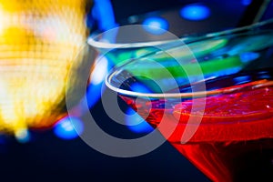 Detail of red cocktail with golden sparkling disco ball background with space for text