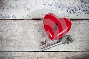 Detail of red heart figure with safe lock on wooden table