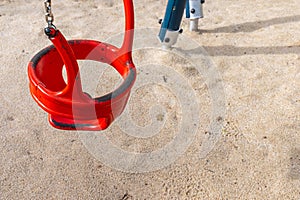 detail of a red metal swing on a children\'s playground