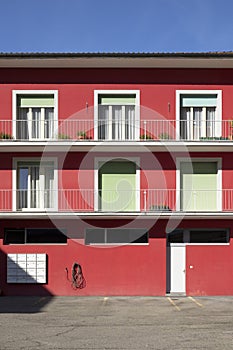 Detail of a red railing house with parking below. There is a letterbox for the entire condominium and a closed white door