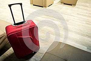 Detail of red suitcase in the airport waiting room. Lounge with lounge chairs