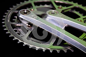 Detail for a road bike on a black background. Old school crankset and chainrings close-up. Soft side light with a slight yellow