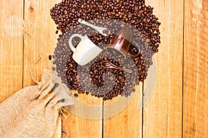 Detail of roasted coffee beans and coffee cup on wooden background, burlap sack, sackcloth bag with coffee beans, top view, copy