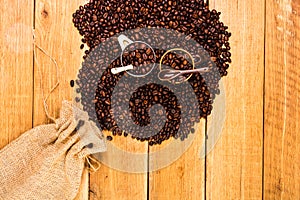 Detail of roasted coffee beans and coffee cup on wooden background, burlap sack, sackcloth bag with coffee beans, top view, copy