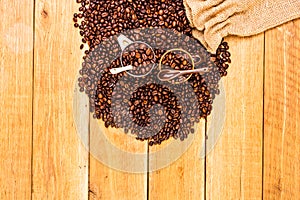 Detail of roasted coffee beans and coffee cup on wooden background, burlap sack, sackcloth bag with coffee beans, top view, copy