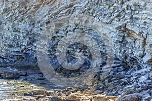 Detail of a rock with variants of blue. Rock full of curves and smooth cuts resulting from the erosive effect of sea.Stones