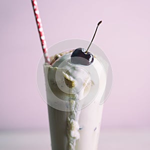 Detail of a root beer float with cherry on top and red paper straw.