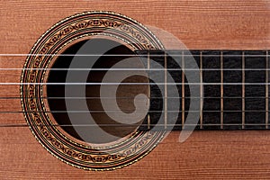 Detail of rosette decal, soundhole and strings on acoustic guitar