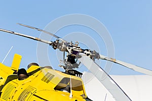 Detail of the rotor of a yellow helicopter with the sky in the background