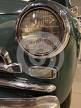 Detail of round headlight of middle class vintage soviet automobile GAZ M20 Pobeda