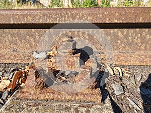 Detail of rusty screws and nut on old railroad track. Rotten tie