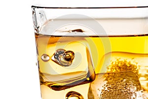 Detail of scotch whiskey in glass with ice cubes on white