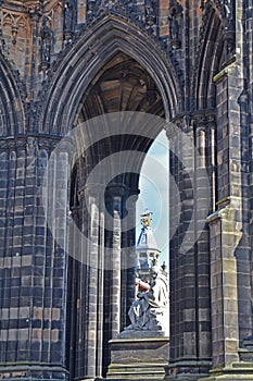 Detail of Scott Monument in Edinburgh, Scotland. Victorian gothic architecture, arch, marble statue of Sir Walter Scott. Blue sky.