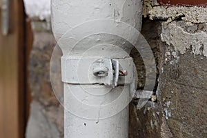 A detail of a screw of a white downpipe