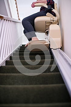 Detail Of Senior Woman Sitting On Stair Lift At Home To Help Mobility