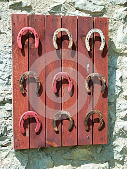 Detail of several old horseshoes hanging on a wooden board.