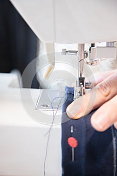 Detail of sewing work execution. Recycling clothes at home to reduce waste and avoid fast fashion. Woman sewing clothes at home.