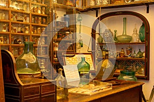 Detail of the shelves full of glass jars and flasks of different colors and shapes in a very old pharmacy