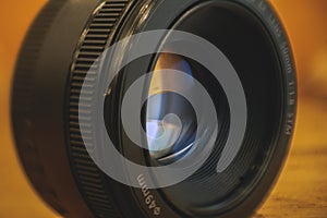 Detail shot of a 50mm photographic reflex camera lens on an orange background