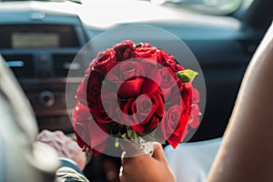 A detail shot of a beautiful bridal bouquet of red roses, held by the bride
