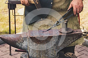 Detail shot of hammer forging hot iron at anvil