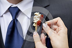 Detail shot of hands pinning on a boutonnniere on a grooms suit photo