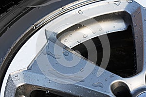 Detail shot of a modern car tires with aluminum rims and water droplets