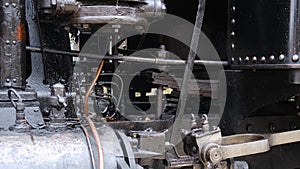 Detail shot of steam train engine with smoke. Black train composition, waiting on a station.