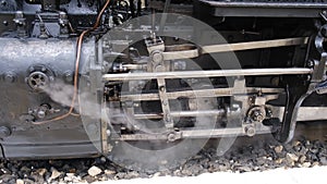 Detail shot of steam train engine with smoke. Black train composition, waiting on a station.
