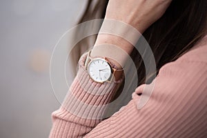 Detail shot of a young fashionable business woman with golden watch on hand