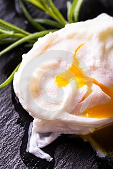 Detail of single poached egg on slate stone