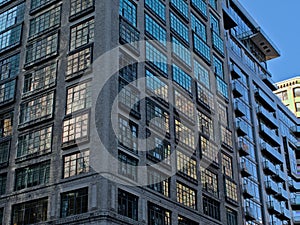 Detail of a skyscraper with reflectio n of other buildings and blue sky in the windows