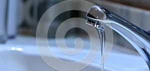 Small stream of water falling from a sink faucet photo