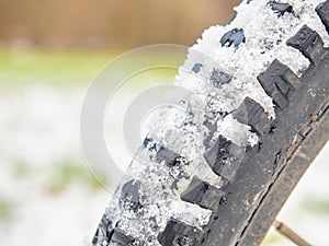 Detail of snow and ice imprinted in a thick winter tire tread on a fatbike