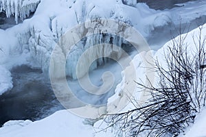 Detail of the snowy banks of the St. Charles River with the Kabir Kouba Waterfall and icicles