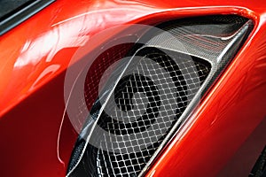 detail of sport car with red metal hood and black air flow intake ornament