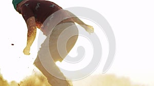 Detail sports male hipster athlete in shorts tries doing tricks with a board on sand dunes slow motion. Sandboard