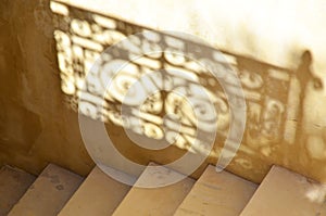 Detail of stairs with the reflection of an ornamented handrail shadowing on the wall photo