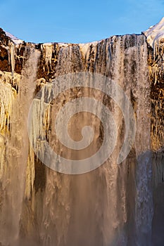 Detail of stalagmites and water falling from the Skógafoss waterfall in Iceland illuminated by late afternoon sunlight
