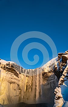 Detail of stalagmites and water falling from the Skógafoss waterfall in Iceland illuminated by late afternoon sunlight