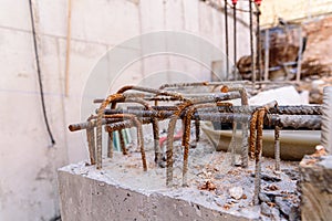 Detail of steel bars inside cement for the reinforced concrete of the foundations of a wall of a building under construction, with